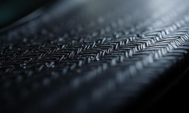 Primer plano de un panel de fibra de carbono con un patrón de tejido intrincado y un acabado brillante.